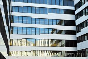 Abstract closeup of the glass-clad facade of a modern building covered in reflective plate glass. Architecture abstract background. Glass wall and facade detail. photo