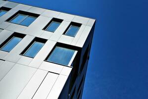 Abstract closeup of the glass-clad facade of a modern building covered in reflective plate glass. Architecture abstract background. Glass wall and facade detail. photo