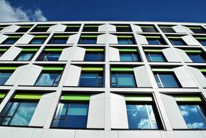 Abstract closeup of the glass-clad facade of a modern building covered in reflective plate glass. Architecture abstract background. Glass wall and facade detail. photo