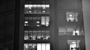 Pattern of office buildings windows illuminated at night. Glass architecture ,corporate building at night - business concept. Black and white. photo