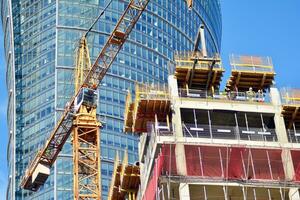 High rise building under construction. Installation of glass facade panels on a reinforced concrete structure. photo