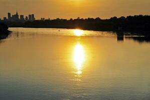 River in the city in at colorful sunset in the background photo