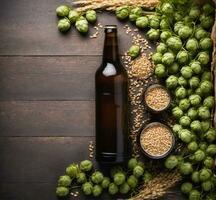 Beer bottle with hop cones and grain on wooden background. Top view photo