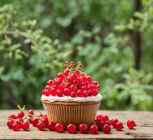 AI generated Cupcake with cream and red currant on a wooden table photo
