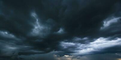 The dark sky with heavy clouds converging and a violent storm before the rain.Bad or moody weather sky and environment. carbon dioxide emissions, greenhouse effect, global warming, climate change. photo