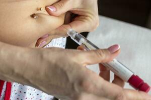 Close up shot of the woman with beautiful hands, preparing hormone medicine and injecting herself to the abdomen with pierced bellybutton. Healthcare photo