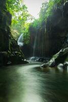 Visit the charm of Indonesia with the Lorong Watu waterfall, North Bengkulu. A narrow alley lined with stone walls, the morning light shines on the waterfall photo