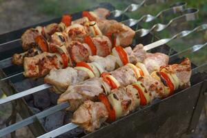 A la parrilla piezas de carne en brochetas, shish brocheta con verduras, Cocinando proceso en brasero foto