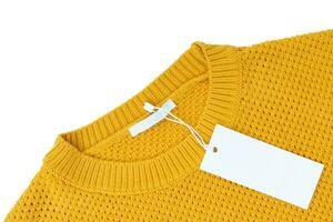 White blank rectangular clothing tag on yellow knitted sweater isolated on white background photo