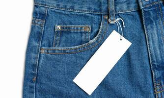 Front side pocket of blue jeans pants and price tag close-up isolated on white background photo