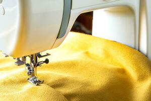 máquina de coser moderna y tela amarilla. proceso de costura, hecho a mano, hobby, bricolaje, negocio, reparación foto