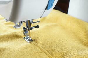 moderno de coser máquina con amarillo terciopelos tela cerca arriba foto