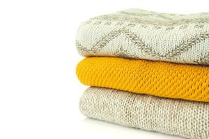 Stack of various sweaters isolated on white background photo
