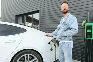 a man charges an electric car photo