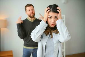 irritado marido es gritos a su esposa con violencia. mujer es cubierta su cara con temor foto