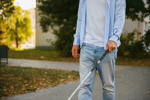 joven hermoso cegado hombre caminando con palo en pueblo foto