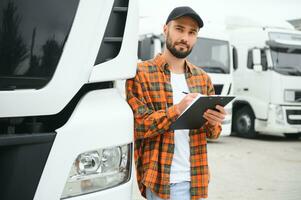 Truck driver checking shipment list while standing on parking lot of distribution warehouse photo