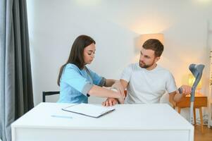 Beautiful young doctor putting a bandage on a male patient's arm after cleaning a wound in a hospital photo