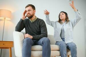 Family quarrel, man and woman sitting on sofa at home. angry woman yells at her husband photo