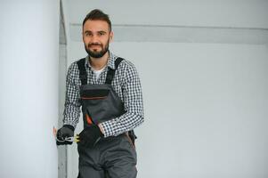 Electrician Builder at work, installation of sockets and switches. Professional in overalls with an electrician's tool. Against the background of the repair site photo