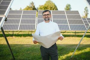 Solar power plant. Man standing near solar panels. Renewable energy photo