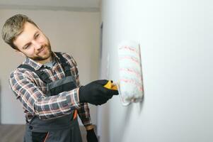 Painter painting a wall with paint roller. Builder worker painting surface with white color photo