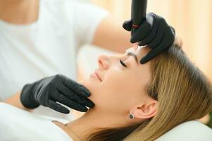 Process of creating permanent brow makeup with a machine at beauty salon photo