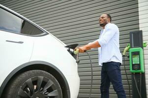 hombre cargando su eléctrico coche a cargar estación foto