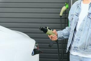 Close Up Of Hand Holding Power Cable For Environmentally Friendly Zero Emission Electric Car photo