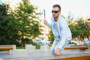 Blind man with a walking stick sitting on a bench at a park photo