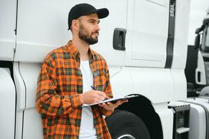 Truck driver checking shipment list while standing on parking lot of distribution warehouse photo