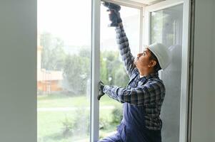 Indian service man installing window with screwdriver photo