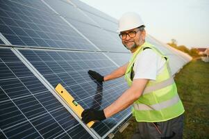 Side view of male worker installing solar modules and support structures of photovoltaic solar array. photo