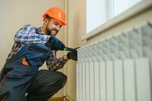 heating system installation and maintenance service. plumber installing radiator photo