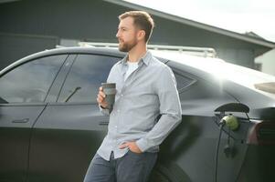 a man charges an electric car photo