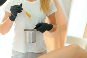 Female cosmetologist holding stick with wax for depilation or sugaring photo