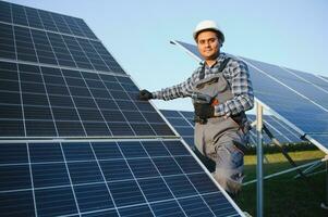 un indio trabajador en uniforme y con herramientas trabajos en un solar panel granja foto