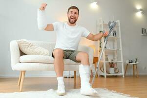 Man with multiple physical limb and body injuries recovers after accident. Happy guy having fun at home photo