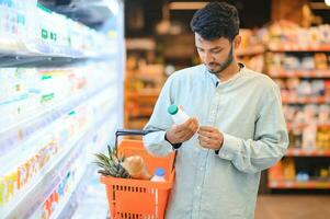 retrato de contento hermoso joven indio a tienda de comestibles tienda o supermercado. foto