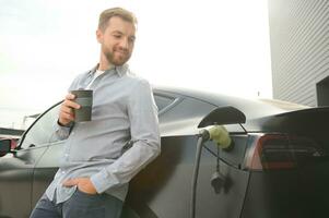 a man charges an electric car photo