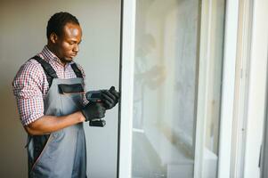 Close-up Of Young African Handyman In Uniform Installing Window photo