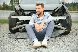 joven hombre conductor en coche accidente cerca roto coche en el la carretera después un coche accidente foto