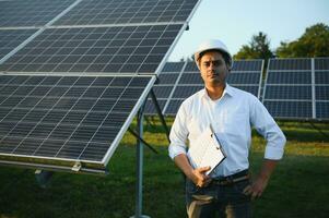 retrato de joven indio masculino ingeniero en pie cerca solar paneles, con claro azul cielo fondo, renovable y limpiar energía. habilidad India, Copiar espacio foto