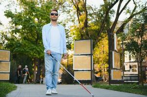 joven hermoso cegado hombre caminando con palo en pueblo foto