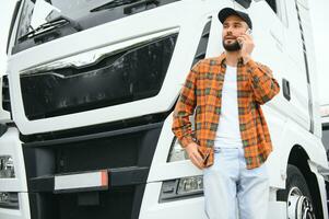 Man trucker talking on the phone by his white truck photo