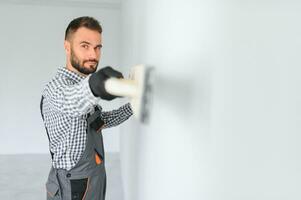 joven trabajador haciendo reparar en habitación. foto