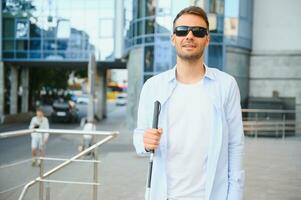 Portrait of a young, handsome blind man walking in the city. The concept of limited physical capabilities. photo