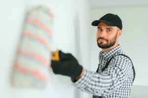 joven trabajador pintura pared en habitación. foto