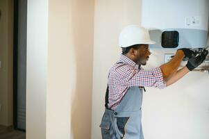 African american worker set up central gas heating boiler at home photo