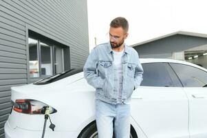 hombre en pie por su eléctrico coche foto